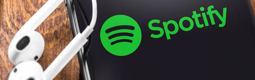 Apple Earpods and iPhone with Spotify logo on the screen. Spotify - online streaming audio service. Moscow, Russia - July 05, 2019